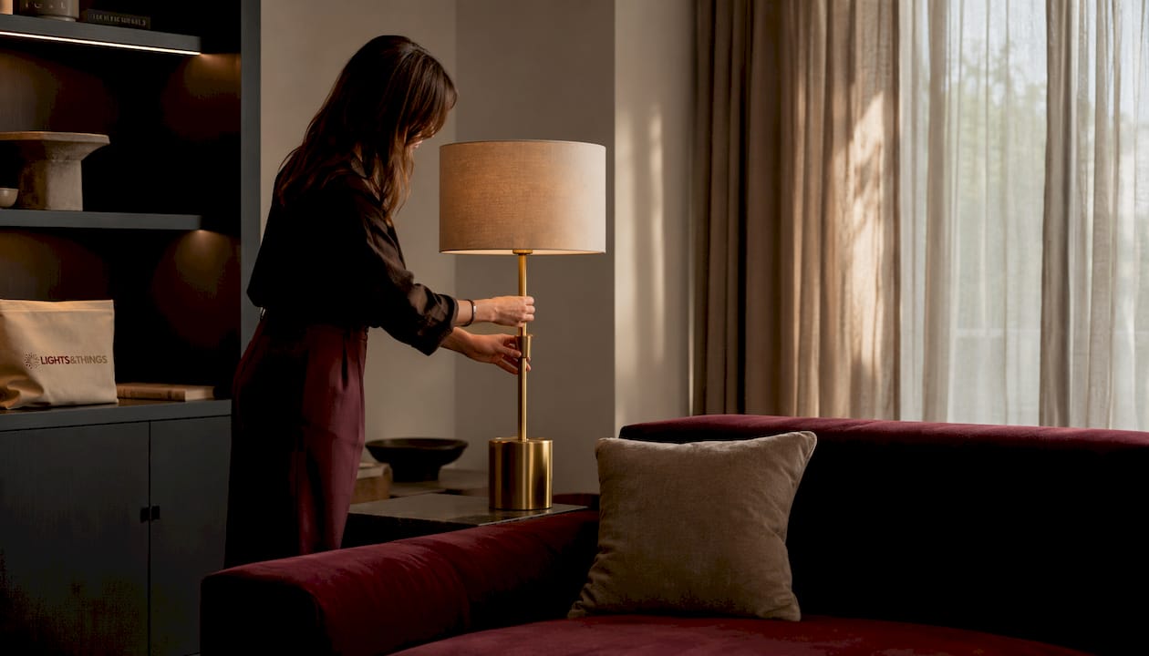 Hands adjusting lamp height near living room sofa