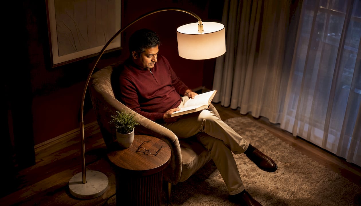 Man reading under arc floor lamp in loft
