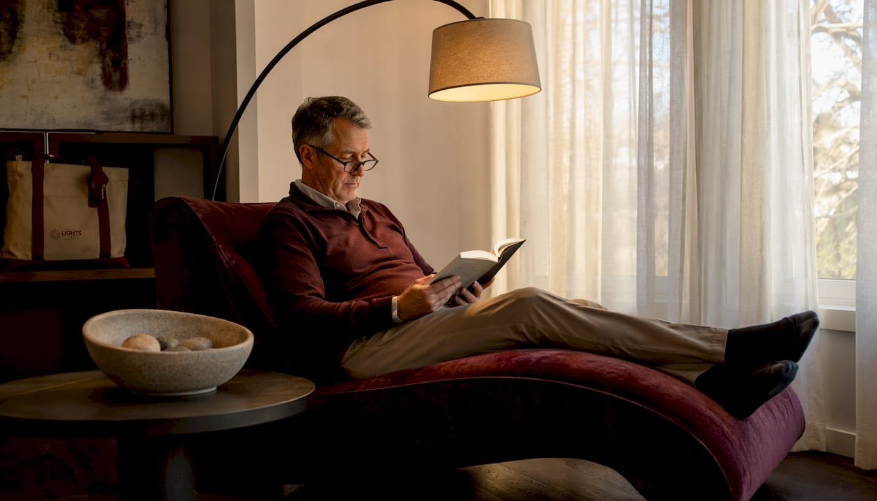 Man reading under task lamp on armchair