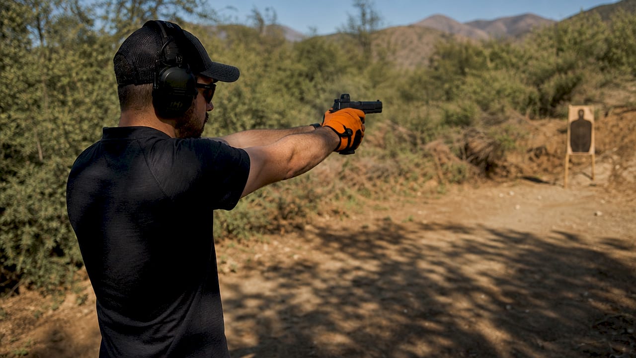 Close profile of pistol shooter gripping and firing