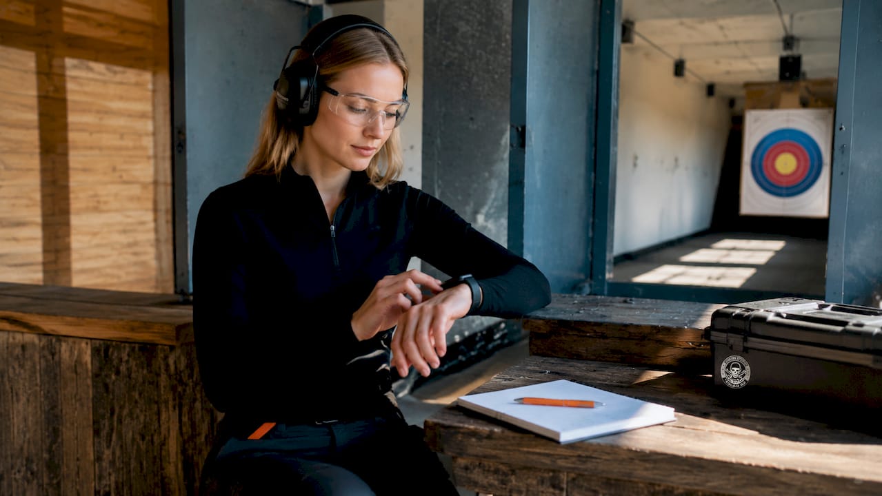 Shooter checking heart rate at indoor shooting range preparation