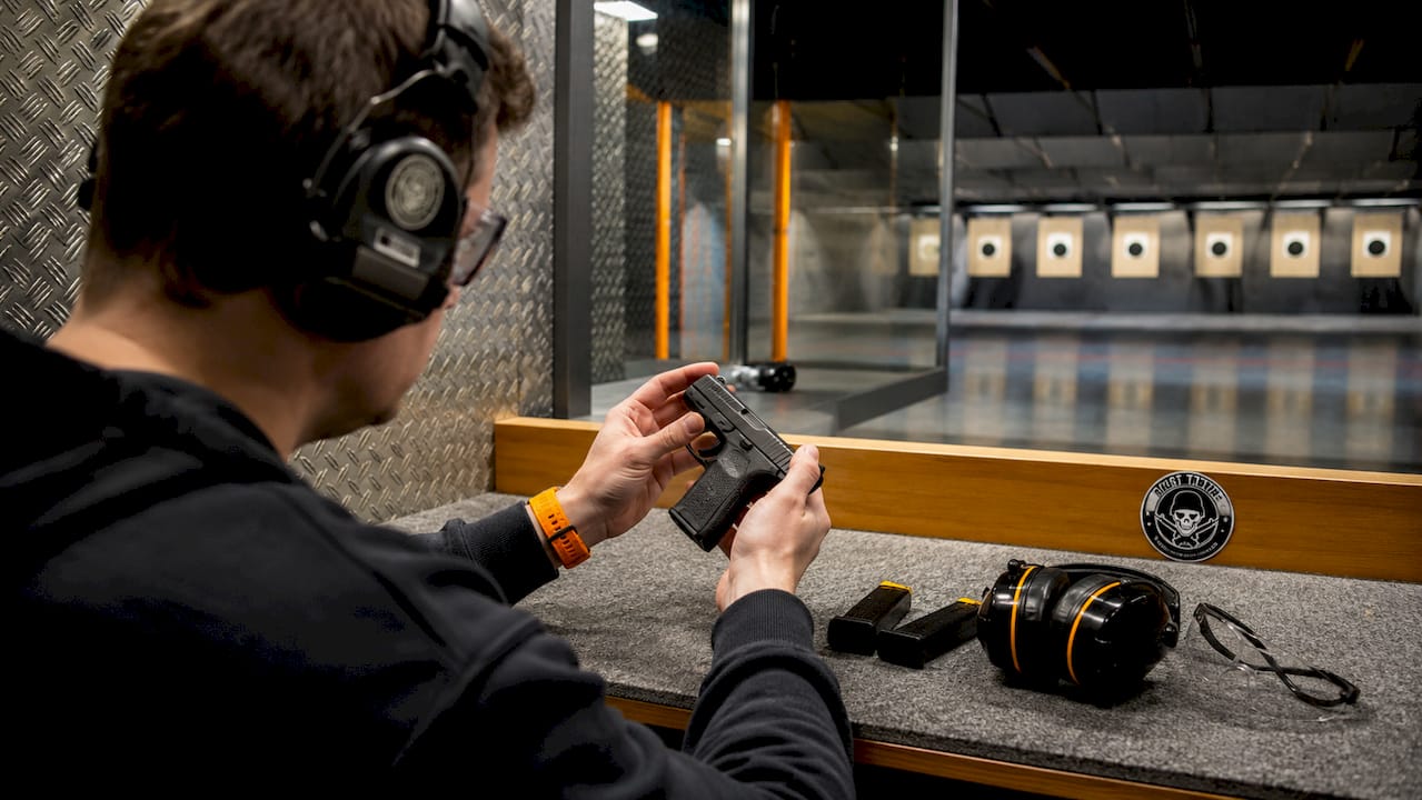 Hands inspecting pistol and magazines on shooting bench