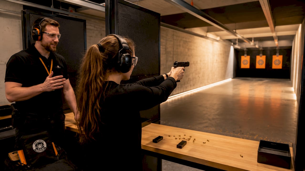 Female shooter training with instructor at indoor lane