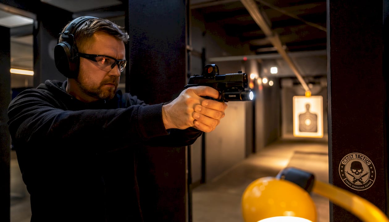 Shooter using optics and lighting tools at night range