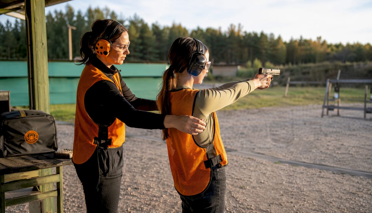 Instructor correcting female shooter's grip and stance
