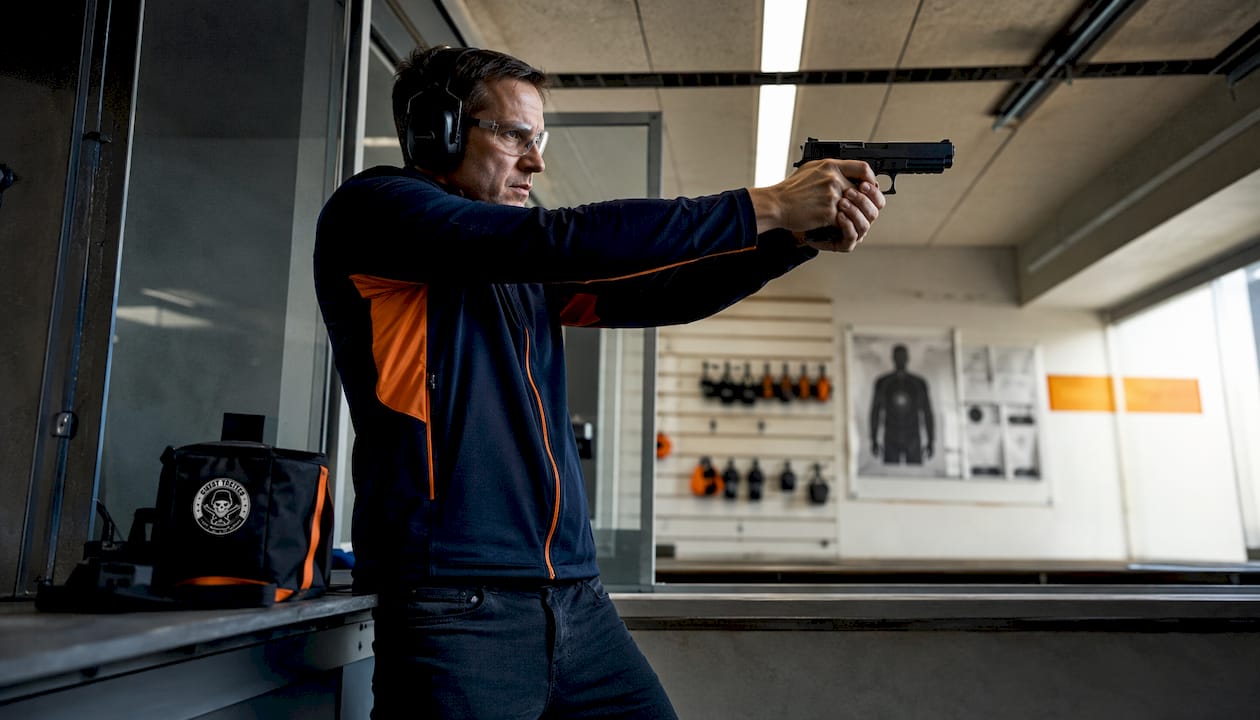 Focused man aiming pistol with concentration