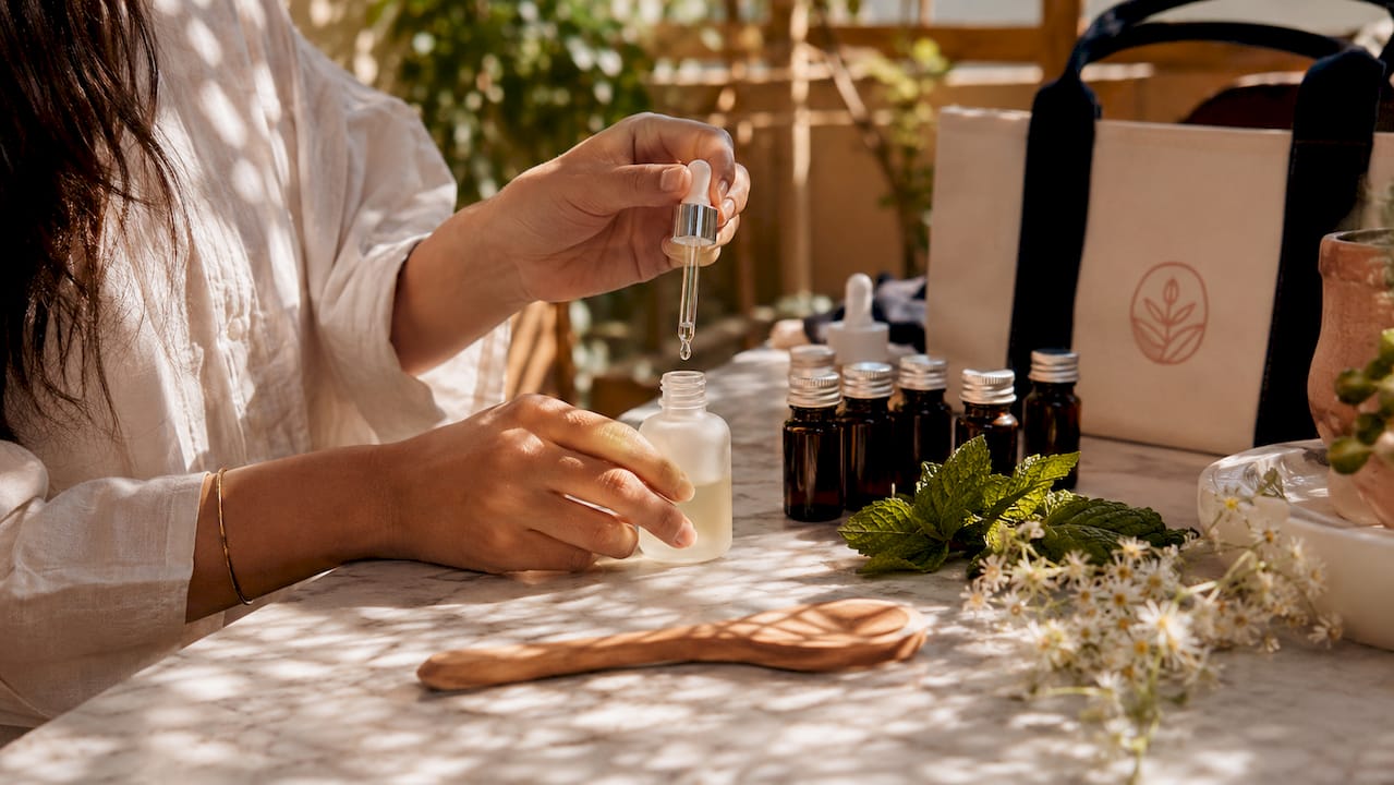 Close-up of hands dropping essential oils into bottle
