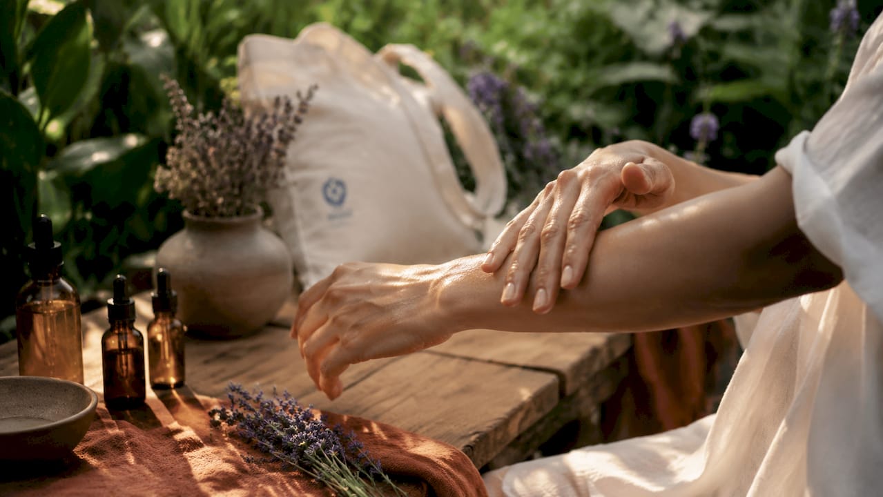 Hands applying body oil on forearm