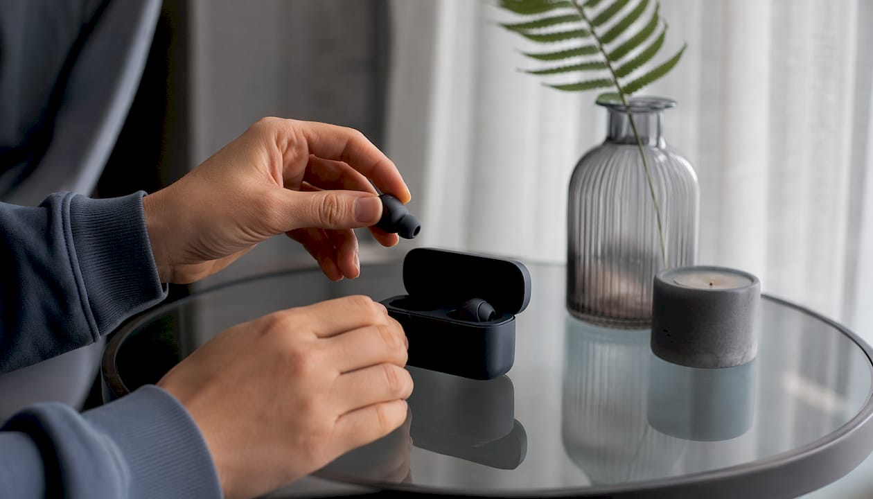 Hands placing Bluetooth sleep earbuds in case
