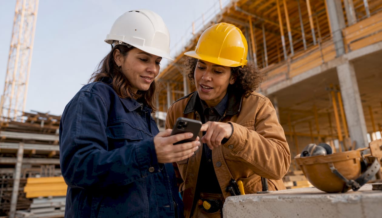 Workers reviewing messages on construction site phone