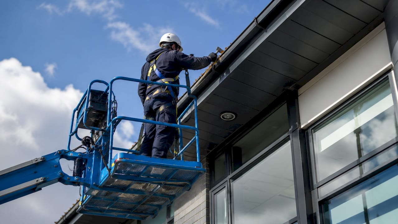 OPSG operative cleaning gutters on office building scaffold