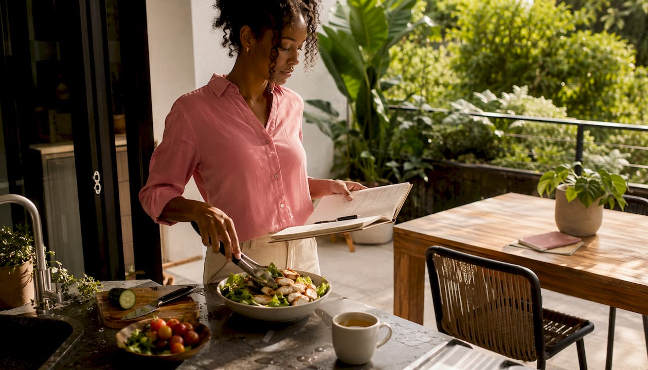 Woman preparing healthy meal with planner nearby