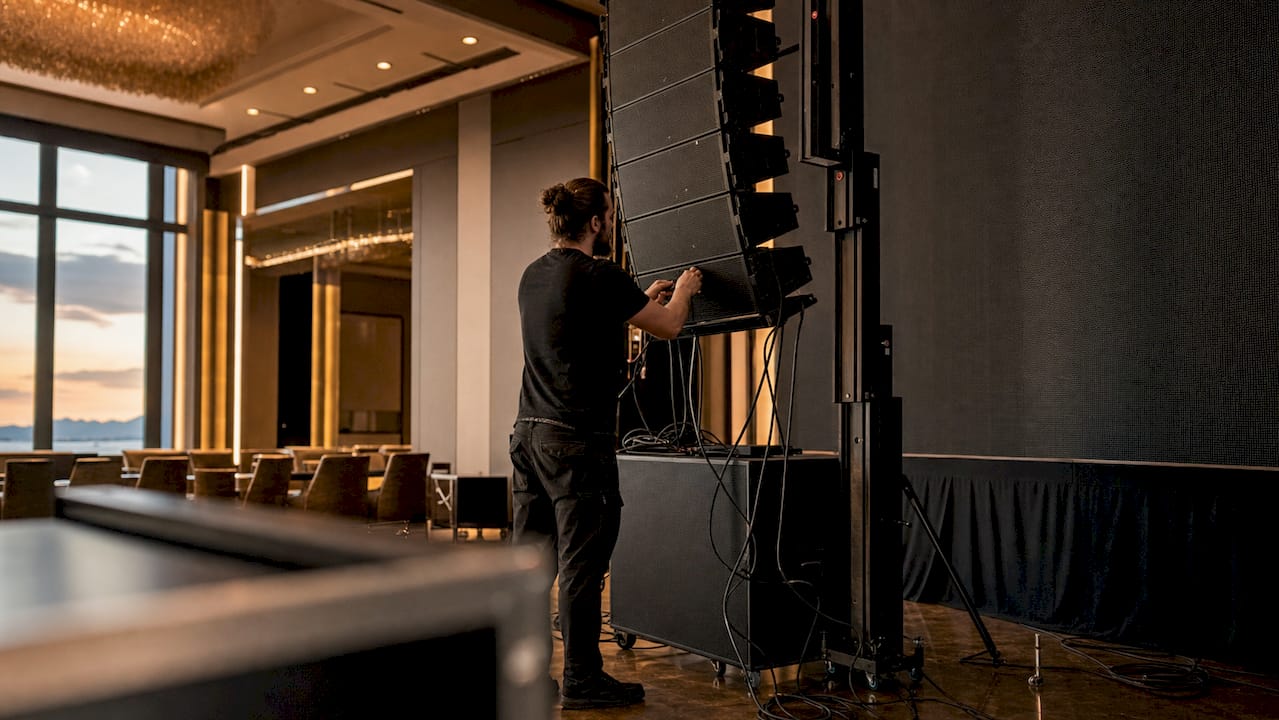 AV technician adjusting speakers next to LED wall