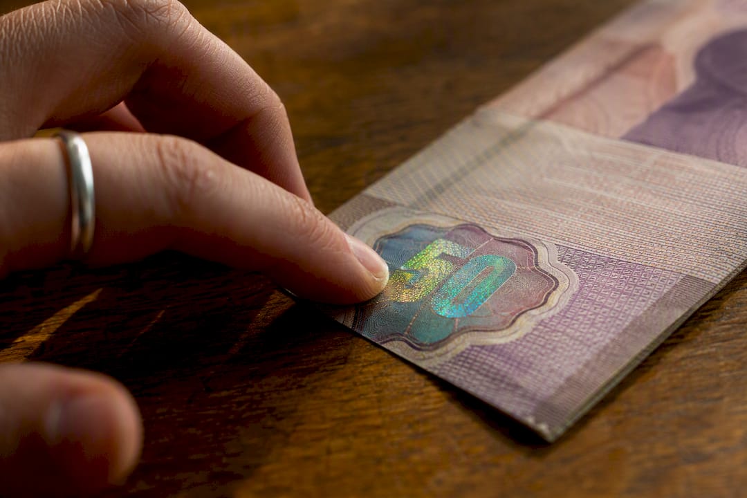 Primer plano del número de un billete cambiando de color al inclinarlo
