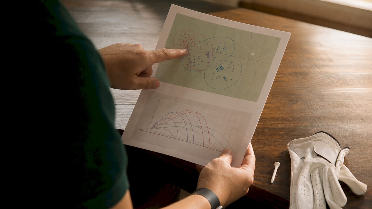 Hands pointing at golf dispersion map printouts