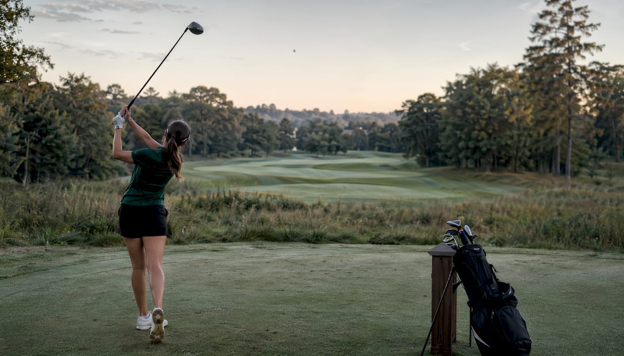 Female golfer hitting tee shot on fairway
