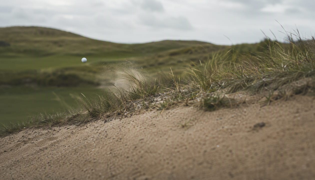 Golf ball low flight over links course in wind