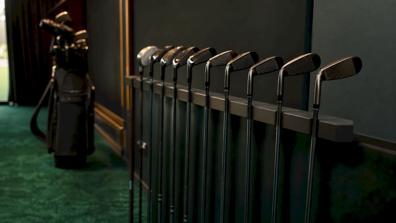 Various driving and utility irons on club rack indoors