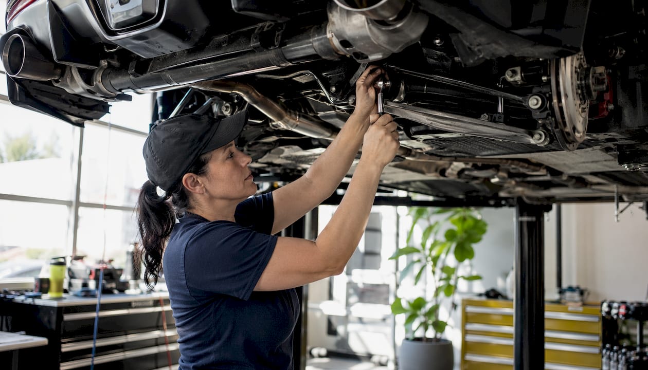 Mechanic tightening sway bar end links under Toyota Supra