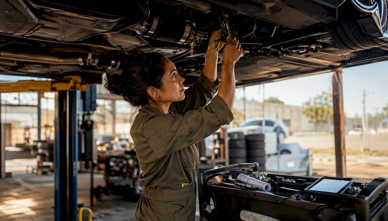 Mechanic adjusting air suspension under lifted BRZ car