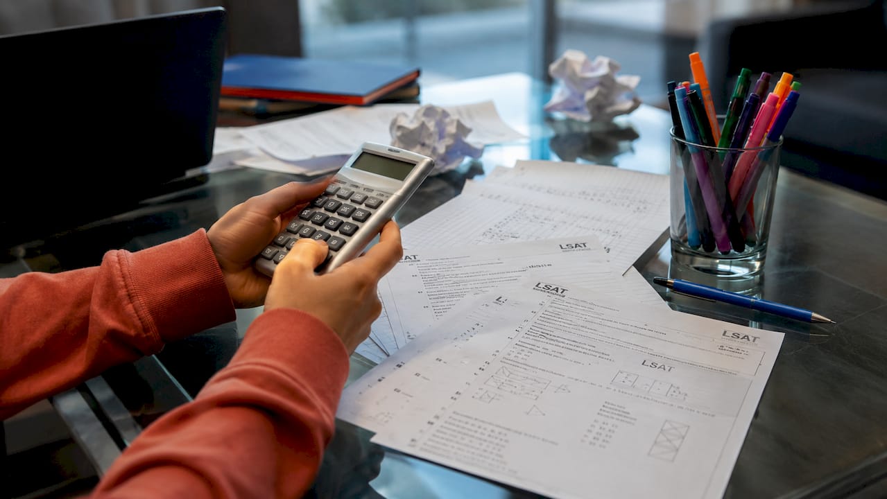 Close-up of hands using calculator on LSAT papers