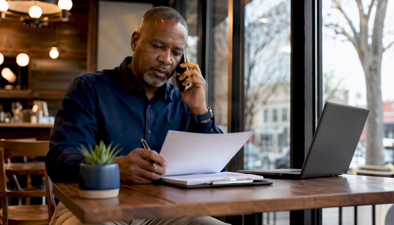 Man on phone filling bail bond application at desk