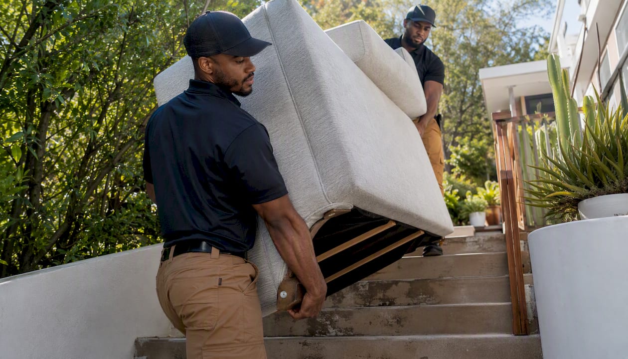 Installers carrying sofa up narrow staircase