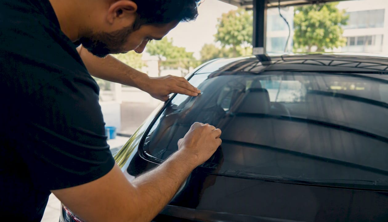 Technician sealing ceramic film on EV panoramic glass