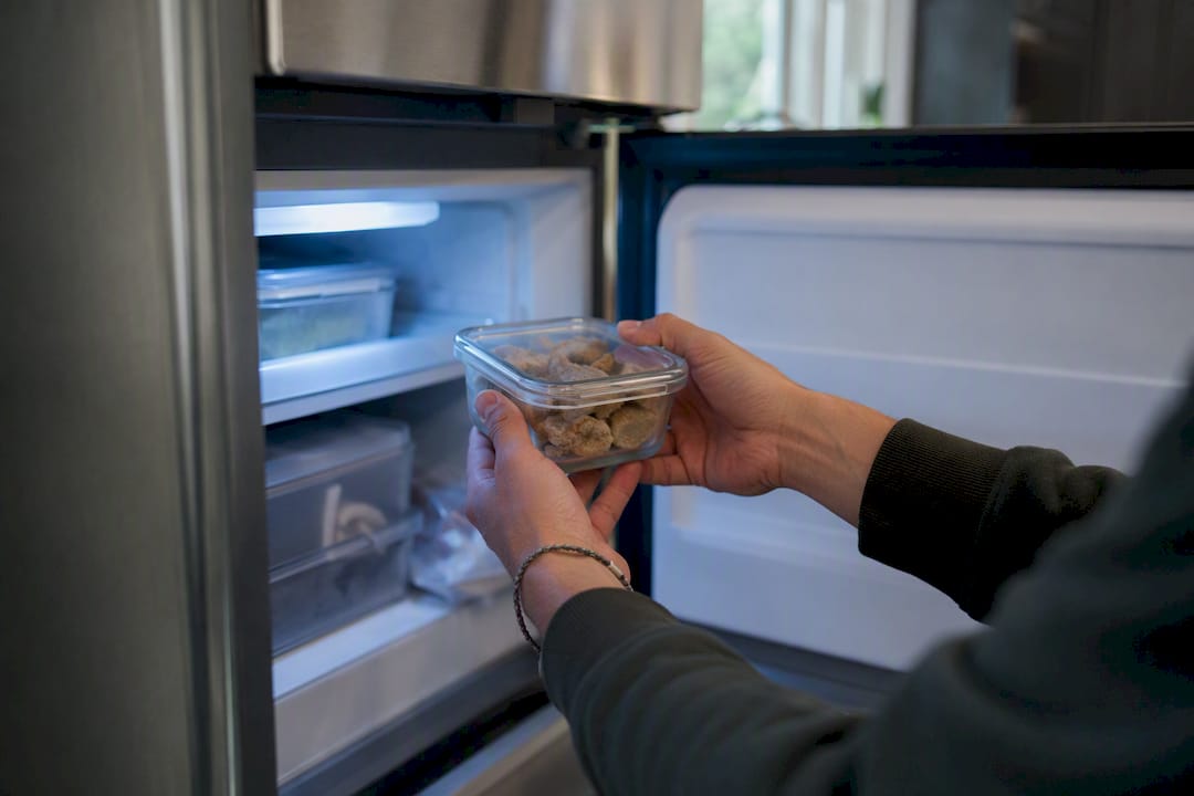 Hands placing airtight container of edibles in freezer