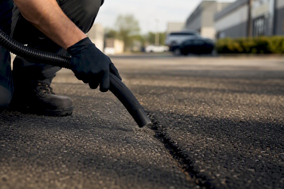 Hand brushing debris out of asphalt crack