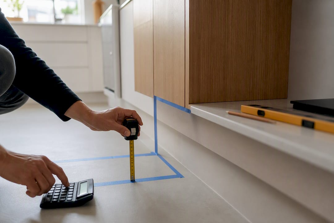 Hands measuring and calculating cabinet height with tools