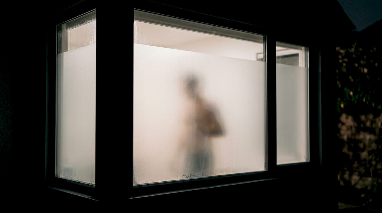 Blurred silhouette behind frosted window film at night