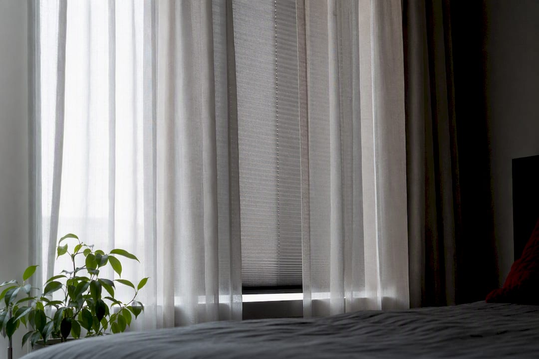 Bedroom window with layered curtains and blackout shade