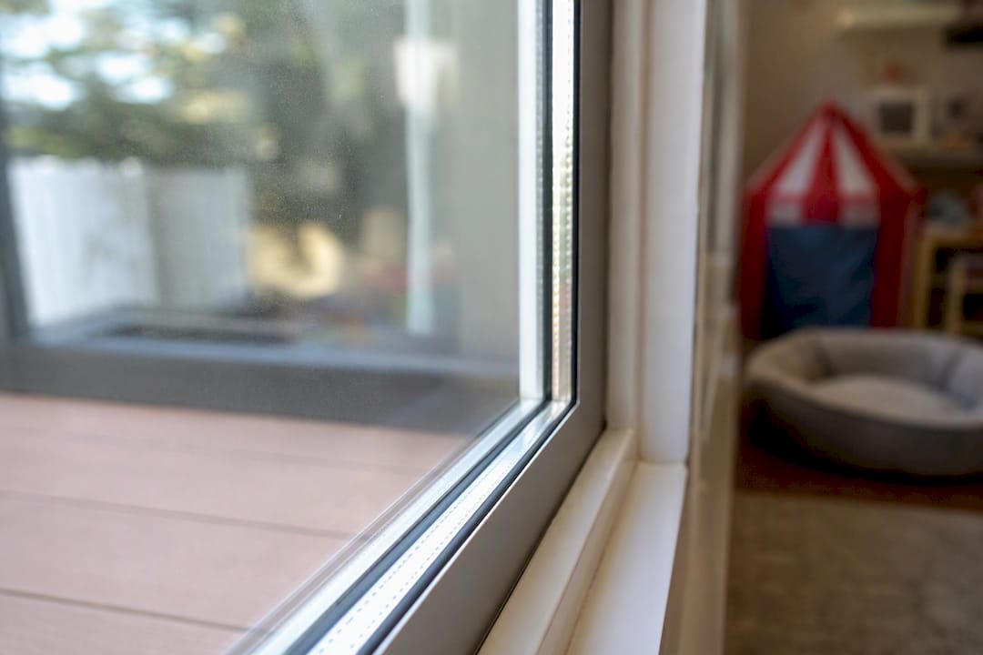 Protected window glass with safety film near crib and pet bed