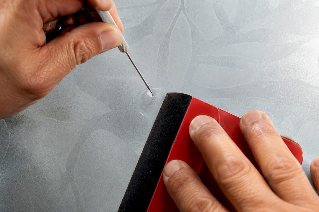 Installer repairing bubble in window film