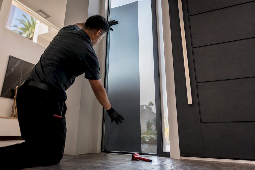 Installer aligning gradient film on tall glass