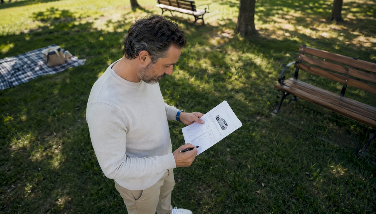 Man reviewing car trade-in appraisal form outdoors