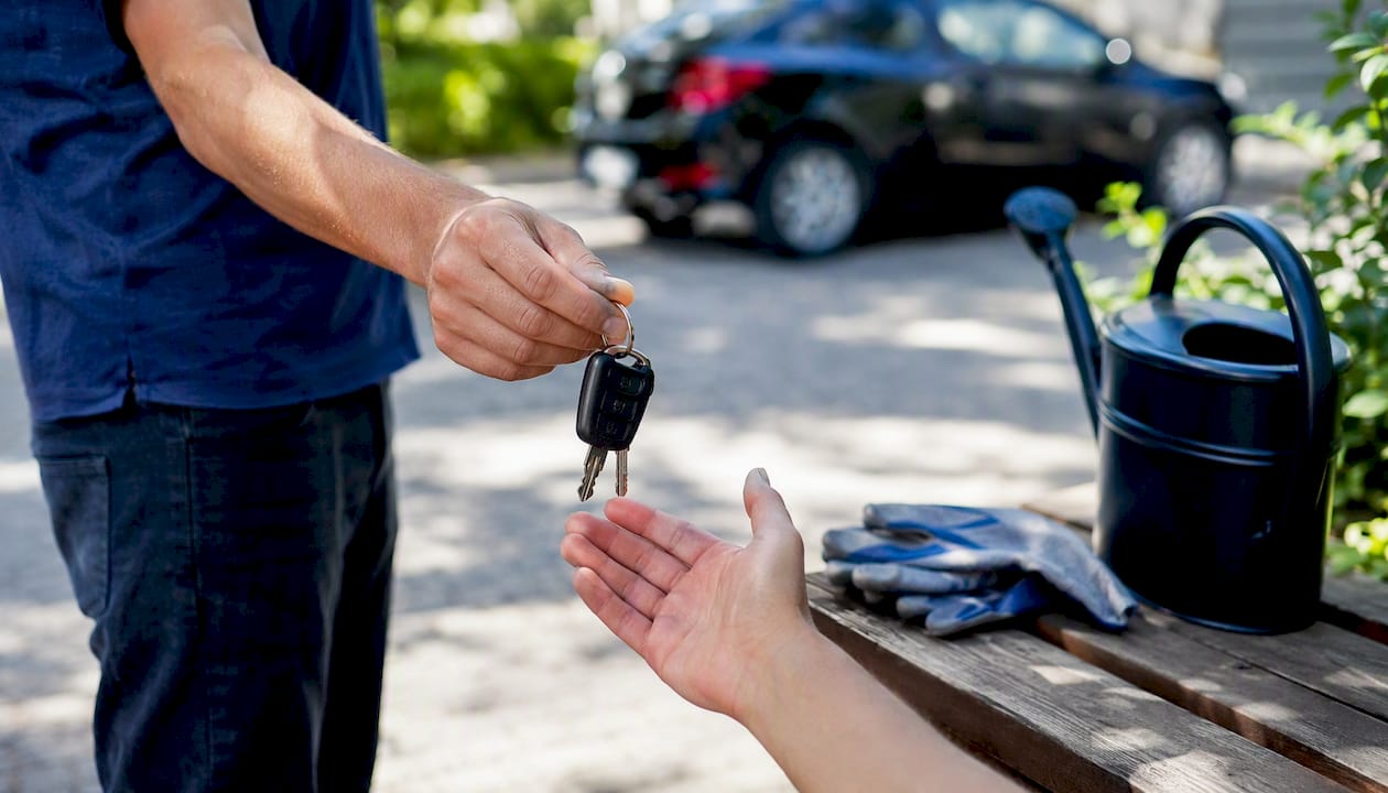 Hand giving car keys in driveway