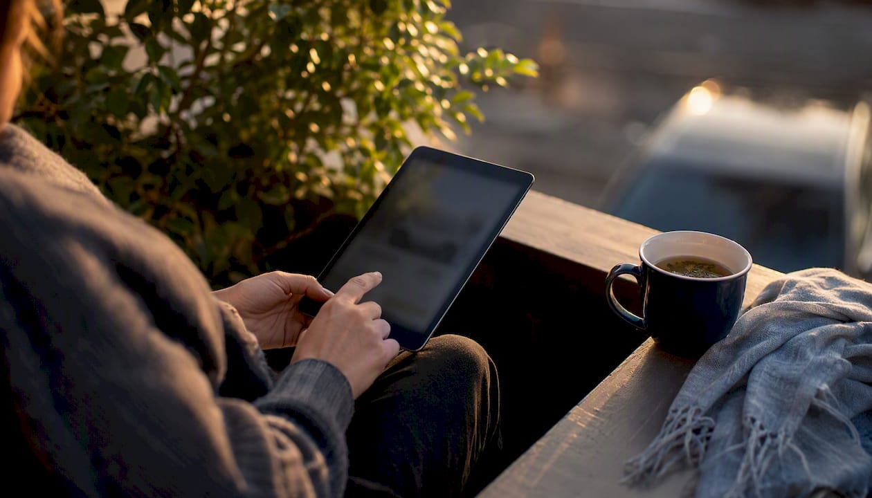 Hands scrolling tablet near car side mirror silhouette