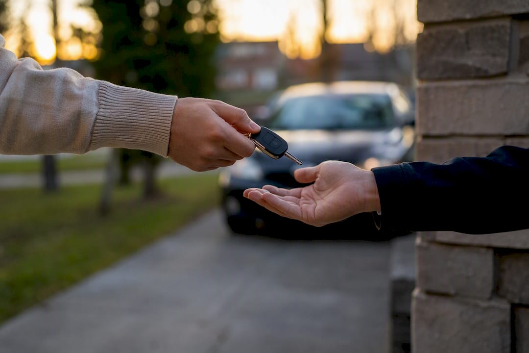 Hands exchanging car keys outdoors
