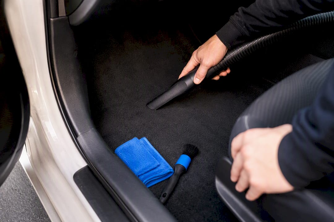 Hands vacuuming vehicle interior before sale