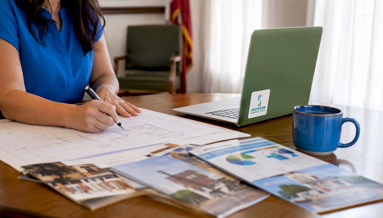 Hands pointing at website plans in local meeting