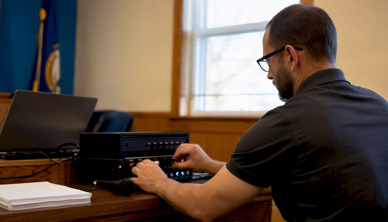 Technician adjusting captioning hardware in small town office