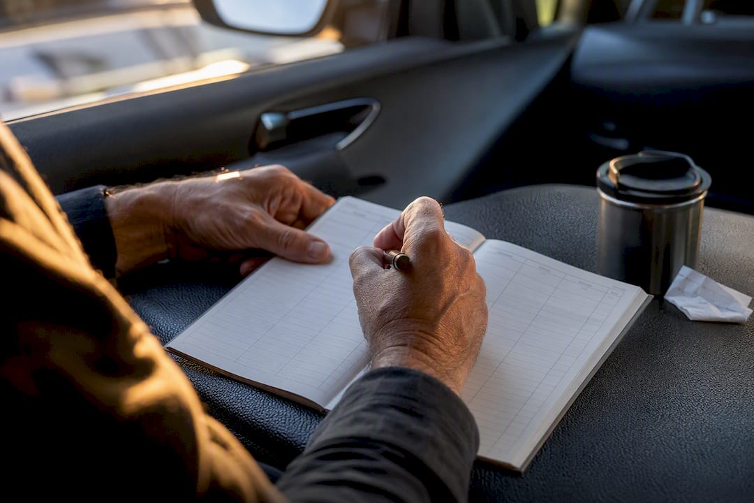 Hands logging vehicle mileage in car