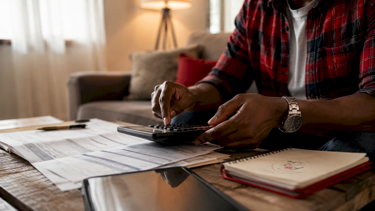 Hands calculating mortgage documents on table
