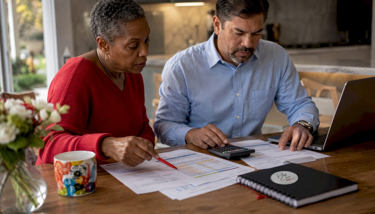Hands comparing mortgage payment calculations on desk