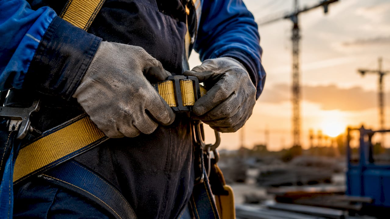 Hands adjusting safety harness buckle