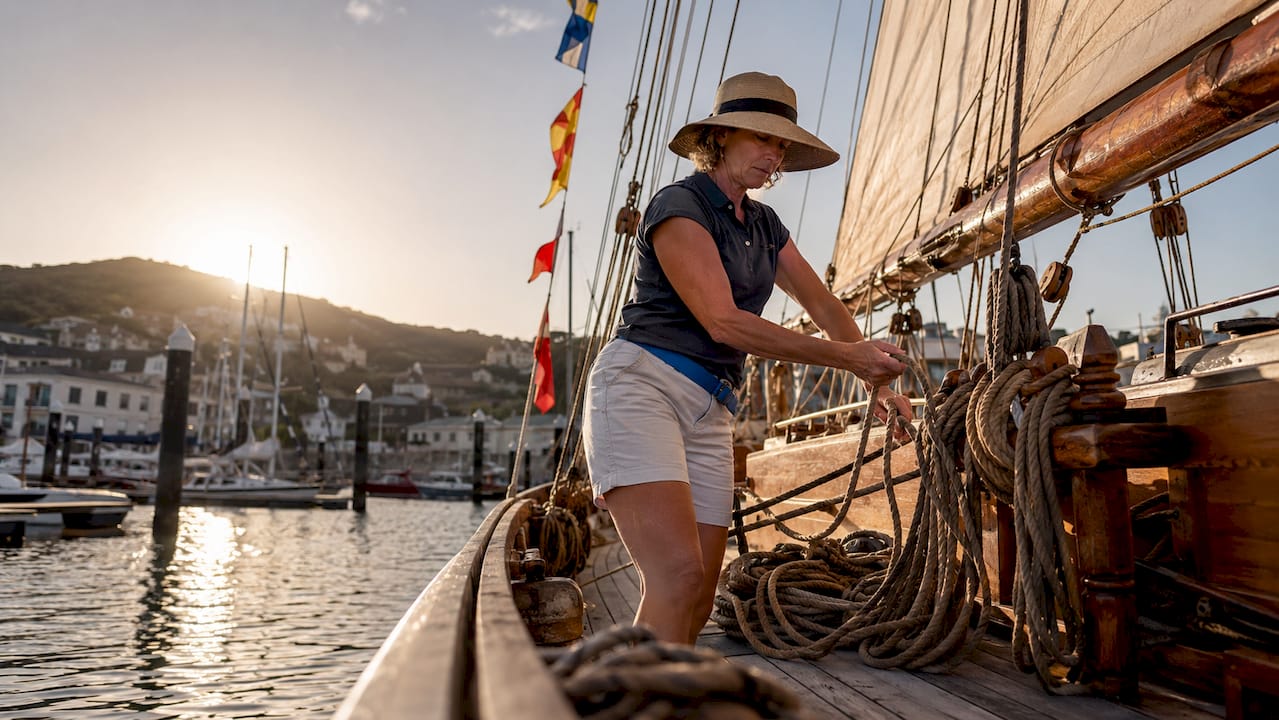 Woman adjusting sail on historic schooner deck