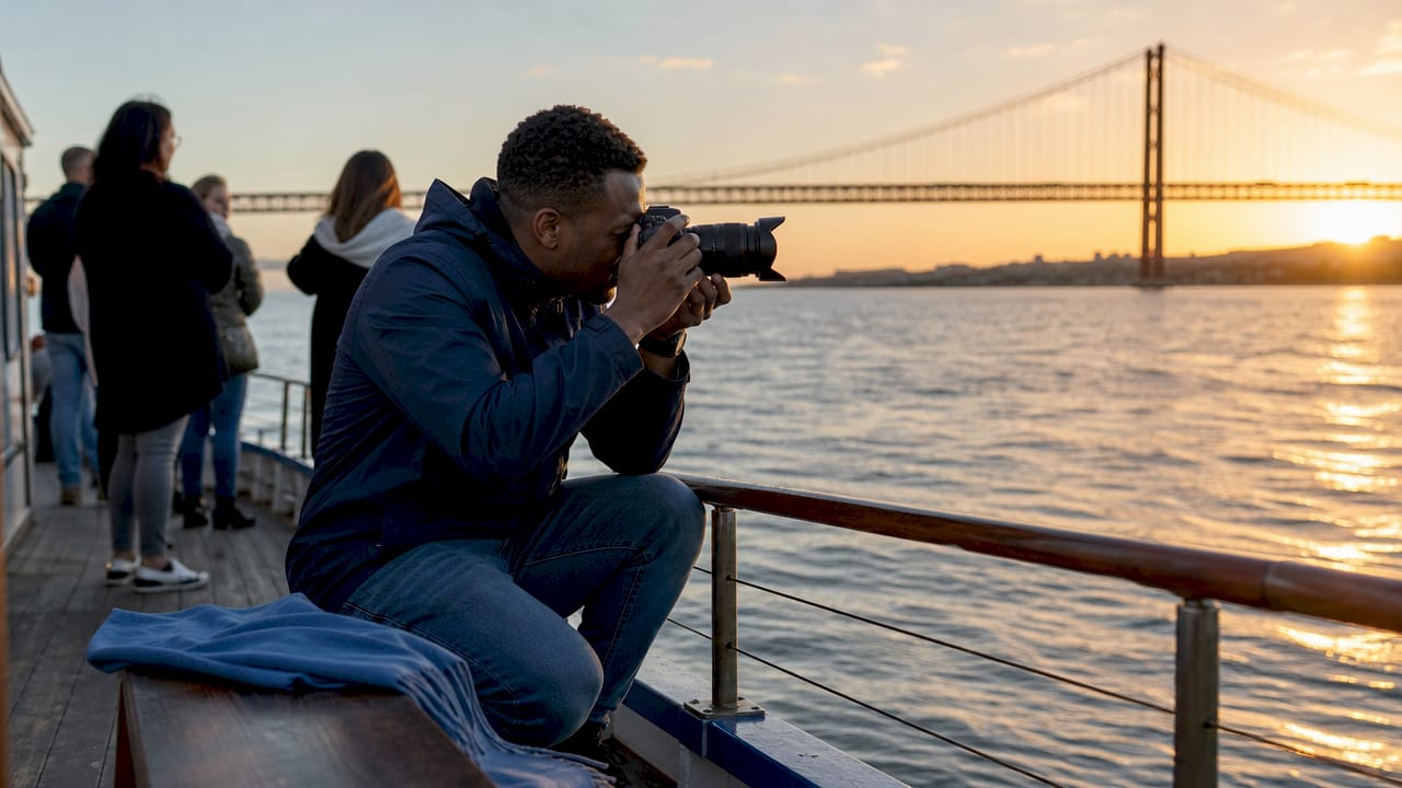 Photographer taking pictures of Tagus River bridge at dawn