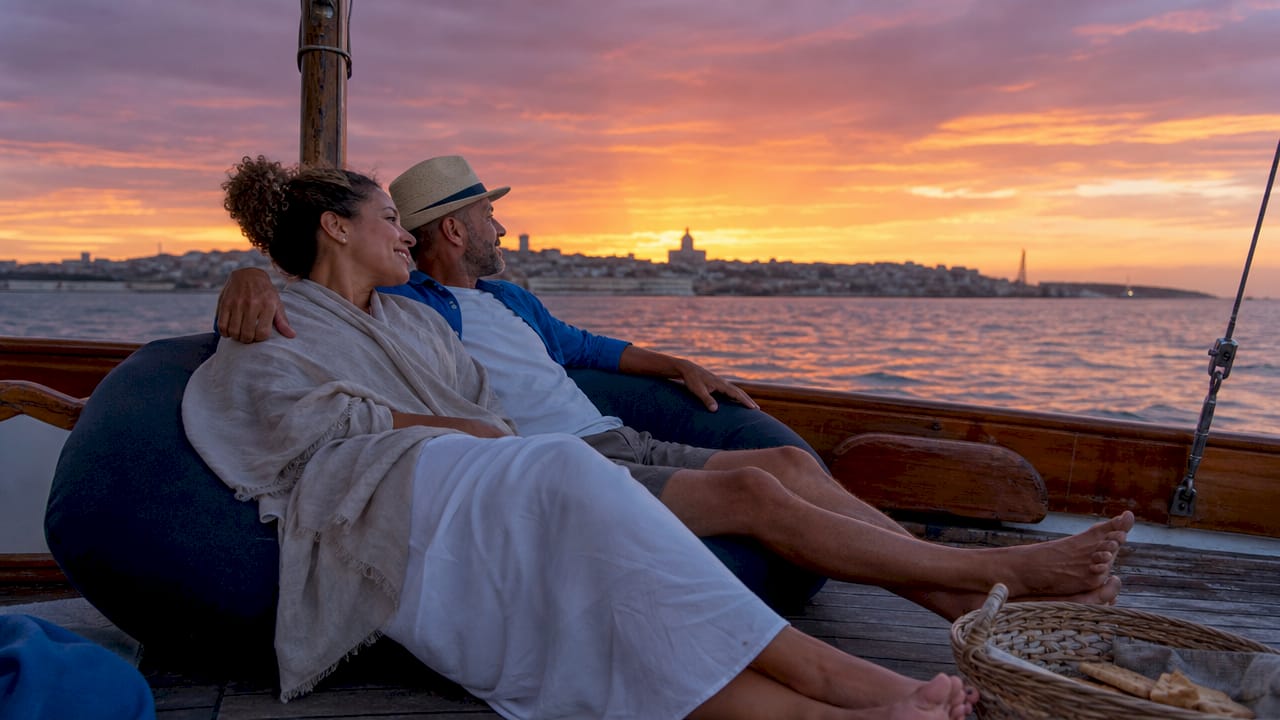 Couple relaxing on sailboat watching Lisbon sunset